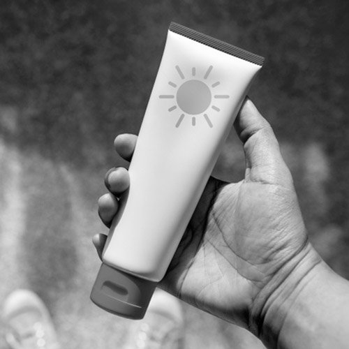 A hand holding a bottle of sunscreen